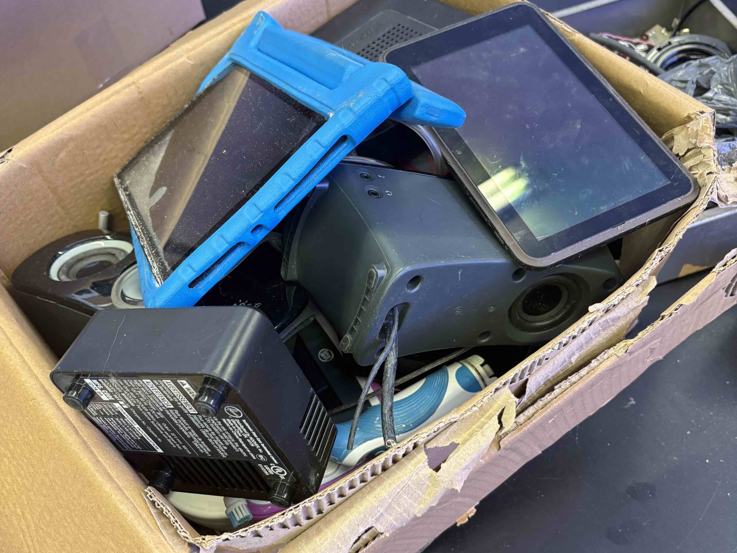 A box of tablets and computer speakers on top of a table.